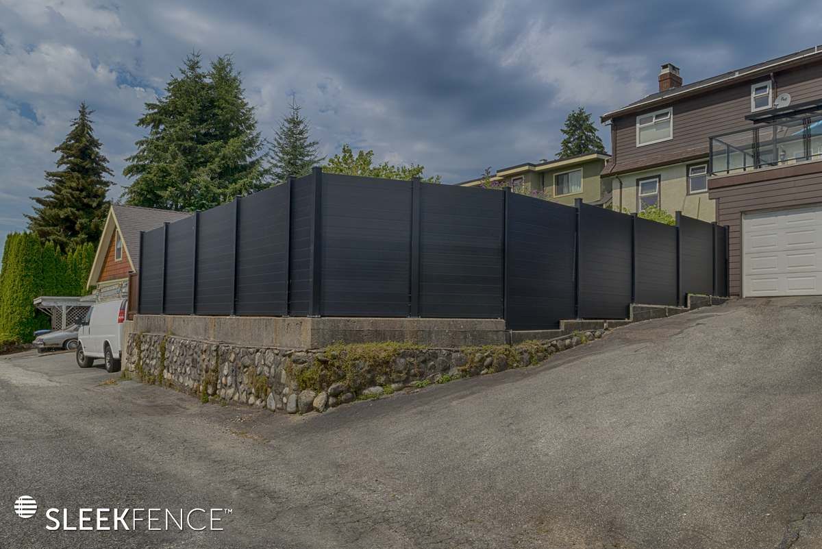 A black fence is surrounding a house on a hill.