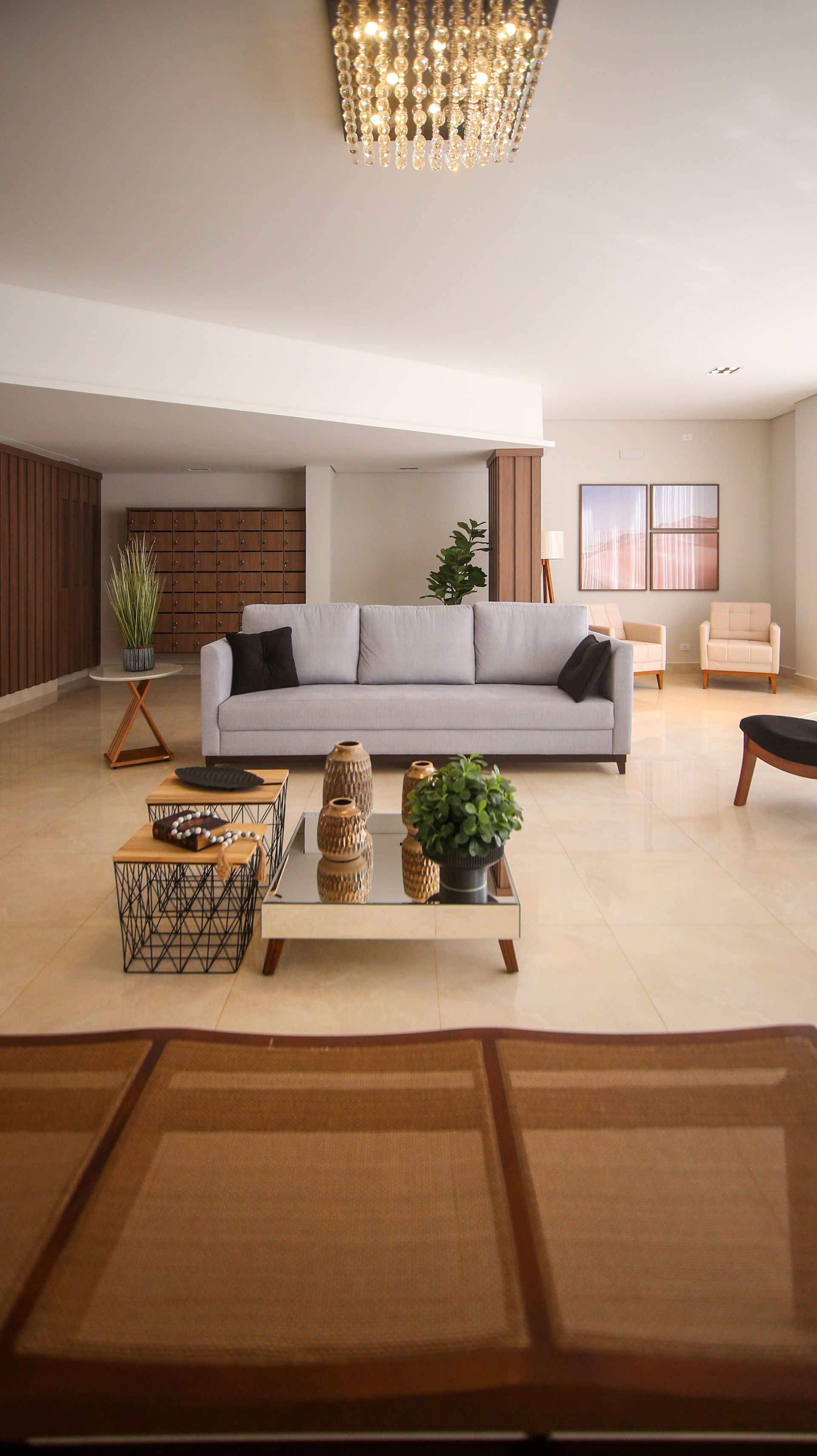 Sala de estar moderna con sofá gris, sillones beige, mesa de centro y luz cálida en el techo.