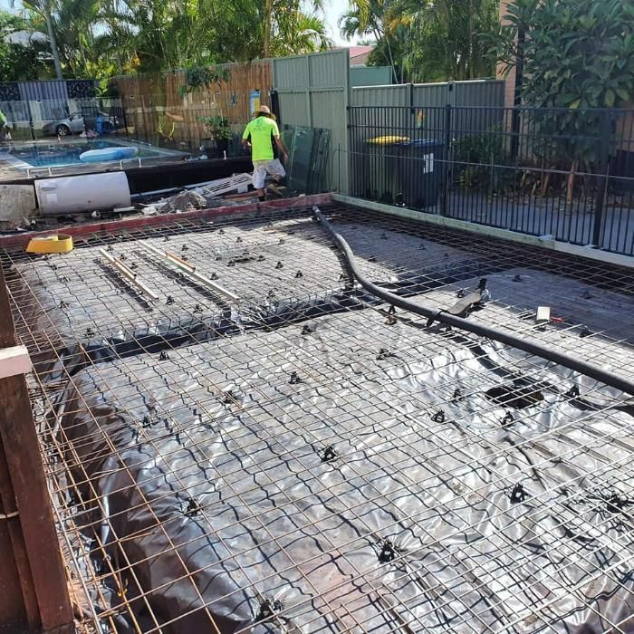 A Man in A Yellow Shirt Is Working on A Concrete Floor — Kontek Constructions in Jimboomba, QLD