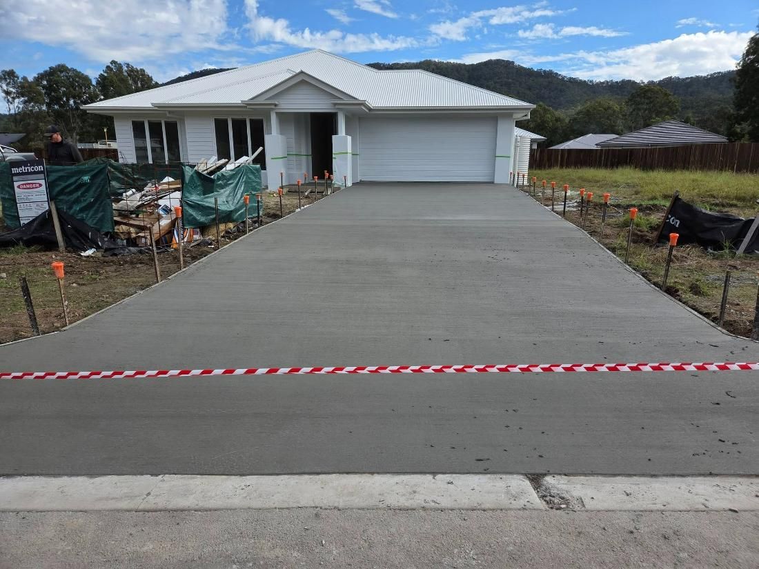 A Concrete Driveway Is Being Built in Front of A House — Kontek Constructions in Brisbane, QLD