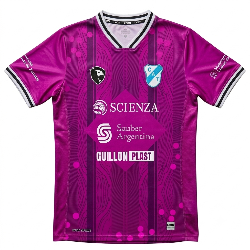 Camiseta de fútbol magenta con ribetes blancos y negros, logotipos de patrocinadores y escudo del equipo en el pecho.