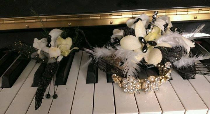 White floral arrangements with black feathers decorating a piano keyboard
