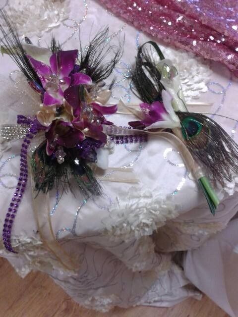 Decorative white cake with purple flowers, black feather accents, and a small bird ornament on a pink tray