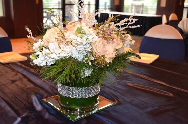 White and blush floral centerpiece on a black table in a decorated banquet room