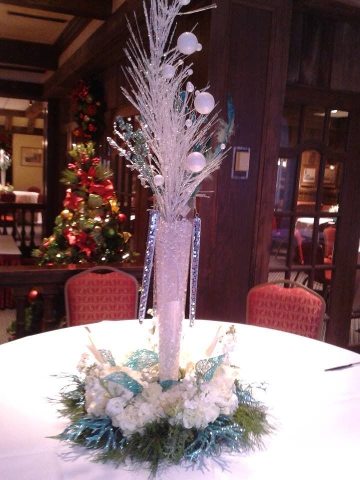Decorative white and silver holiday centerpiece on a round table in a warmly lit restaurant