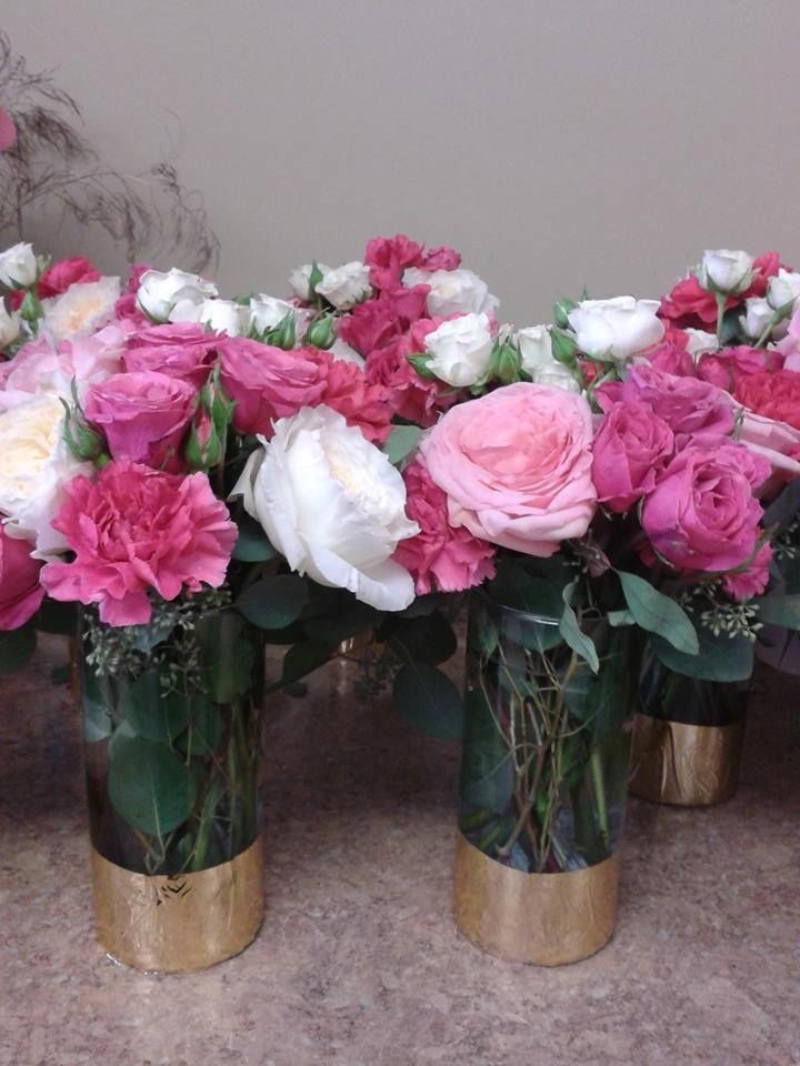 Pink and white flower bouquets in gold vases on a tabletop
