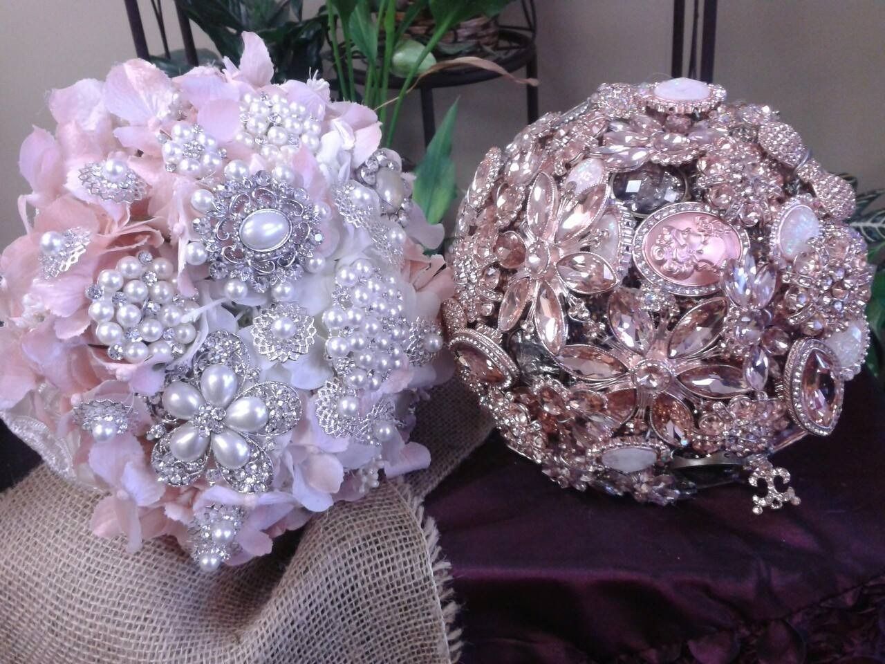 Two jeweled floral brooches in pink, silver, and rose gold on folded fabric