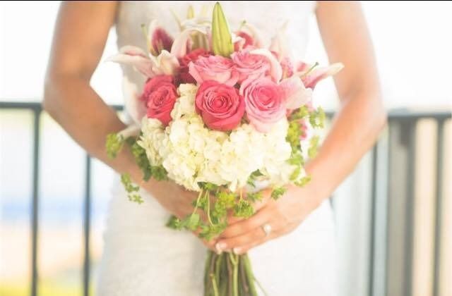 Bride holding a pink and white floral bouquet at a wedding