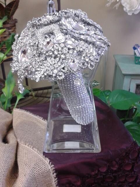 Silver beaded bouquet centerpiece in a square glass vase on a maroon cloth