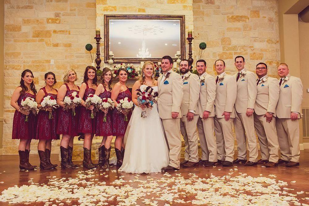 Wedding party posing indoors with bride in white and attendants in burgundy dresses and beige suits