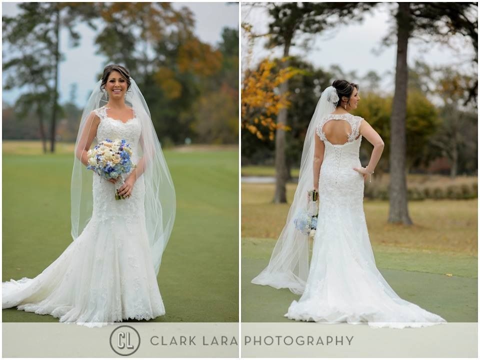 Bride in white gown and veil holding bouquet, posing outdoors on a golf course.