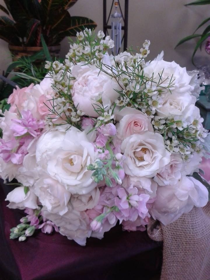 Soft pink and white floral bouquet with roses and delicate greenery, arranged in a vase on a table