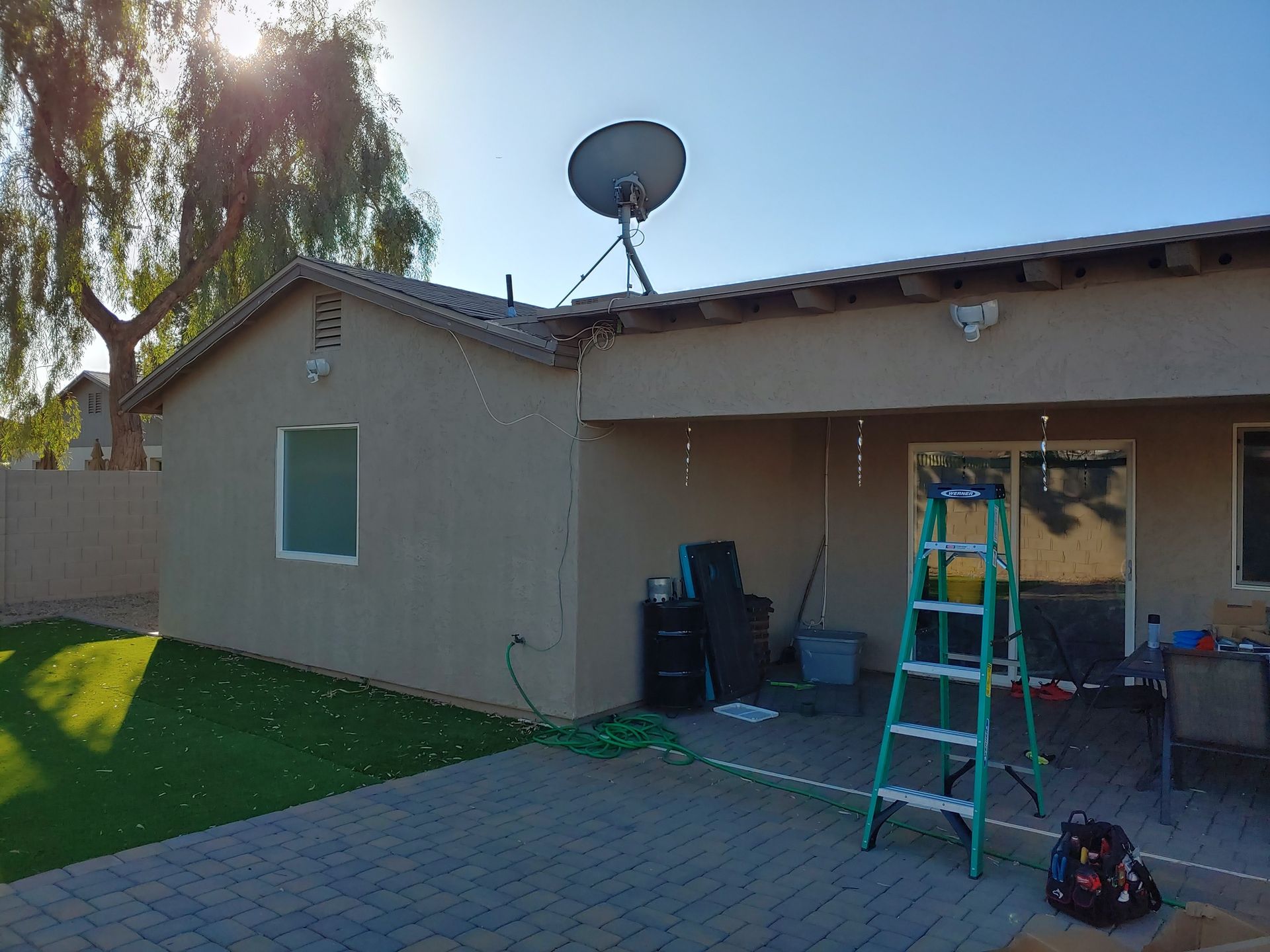 A ladder is sitting in front of a house with a satellite dish on top of it.