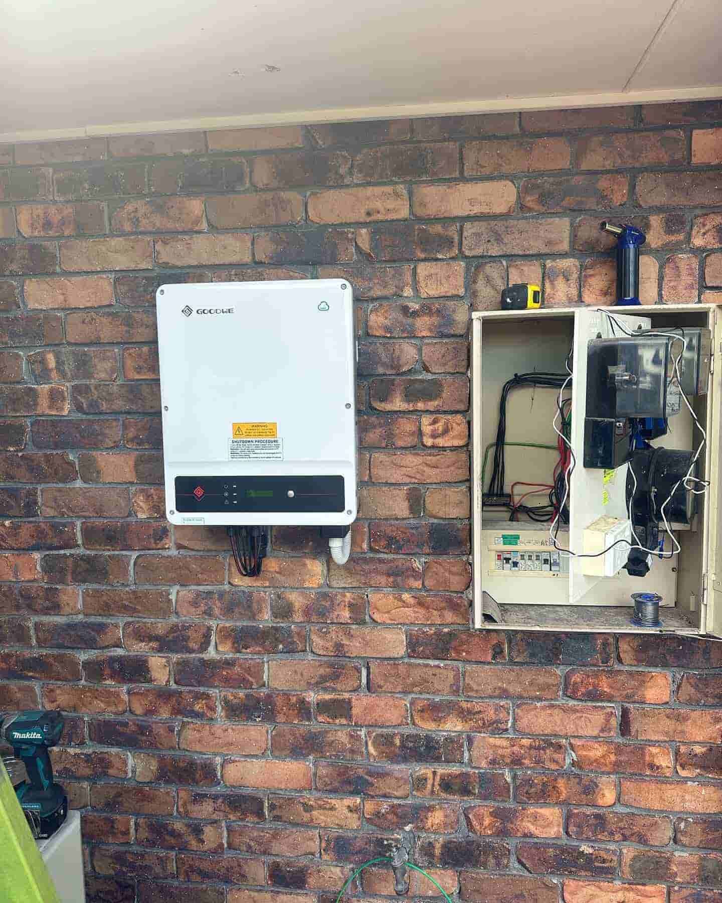 Brick wall with a white wall-mounted device and an open electrical panel beside it — Grand Casa Electrical Solar & Batteries In Ballina, NSW