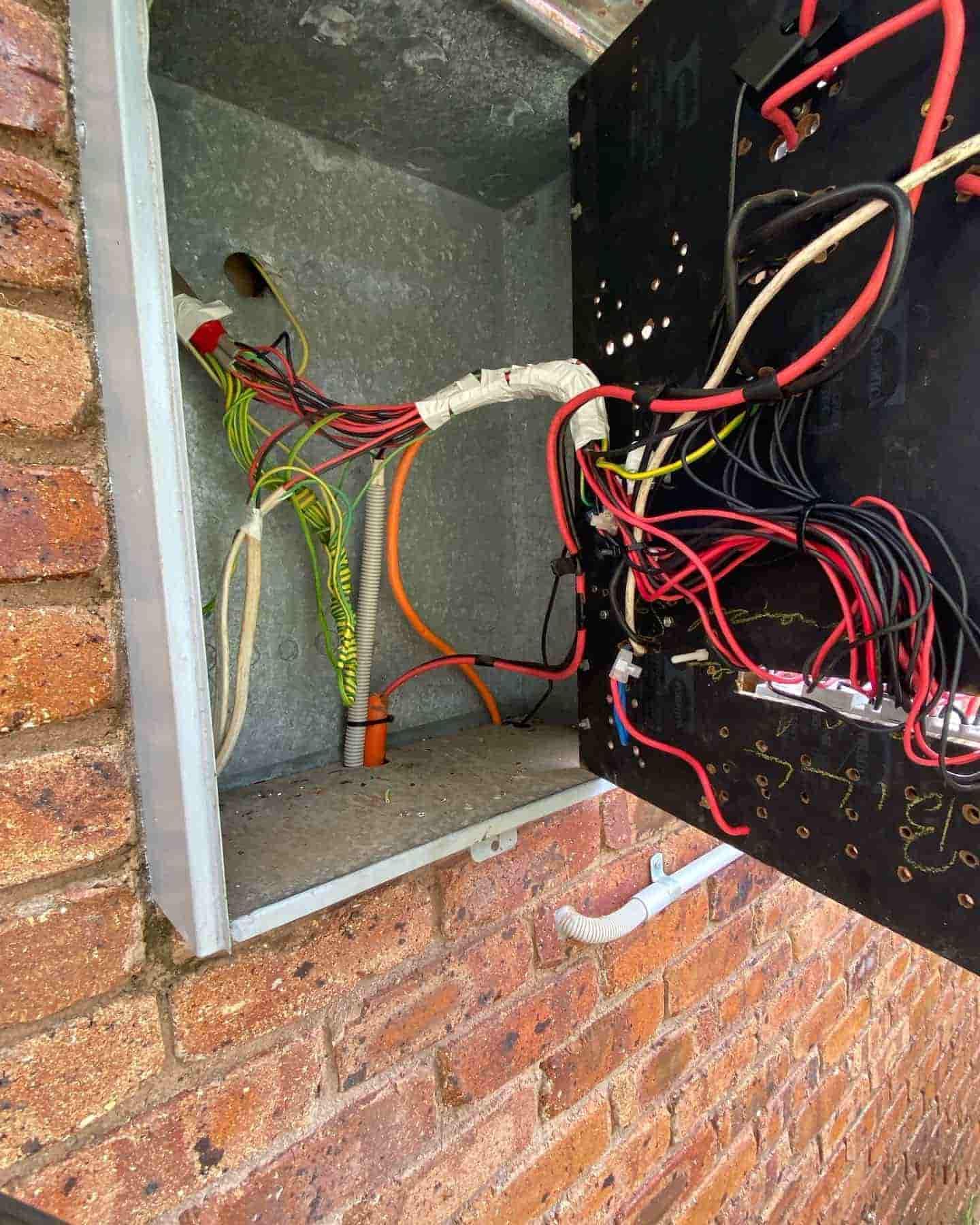 A Box With A Lot Of Wires Coming Out Of It Is Sitting On A Brick Wall — Grand Casa Electrical Solar & Batteries In Ocean Shores, NSW