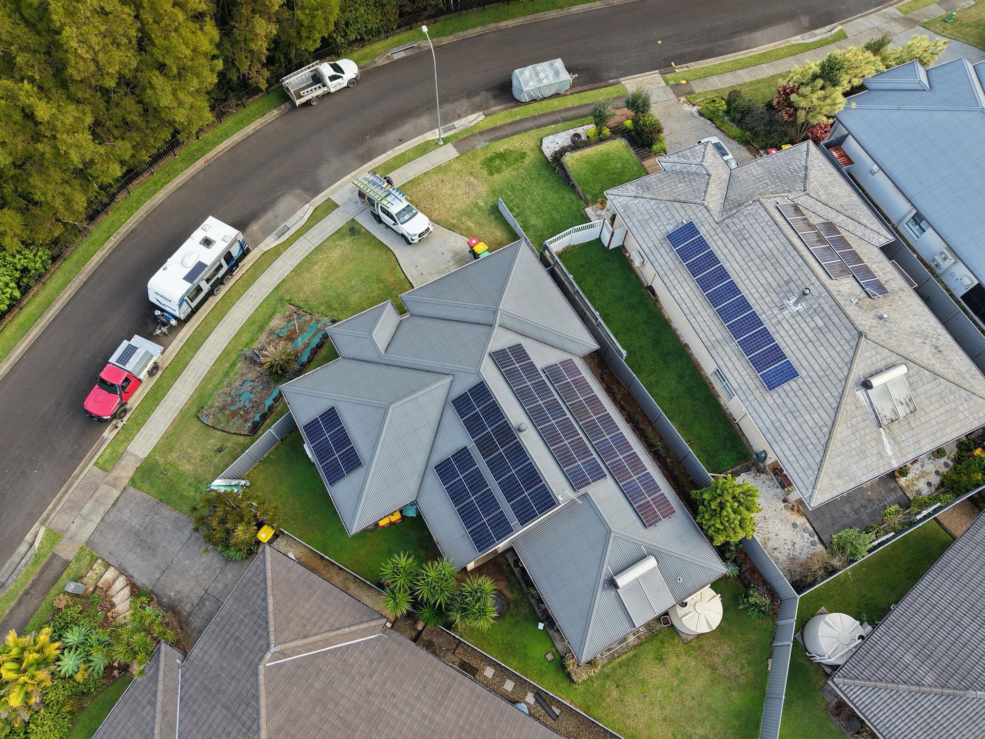 Aerial View of Two Houses With Solar Panels Beside a Road and Parked Cars — Grand Casa Electrical Solar & Batteries In Armidale, NSW