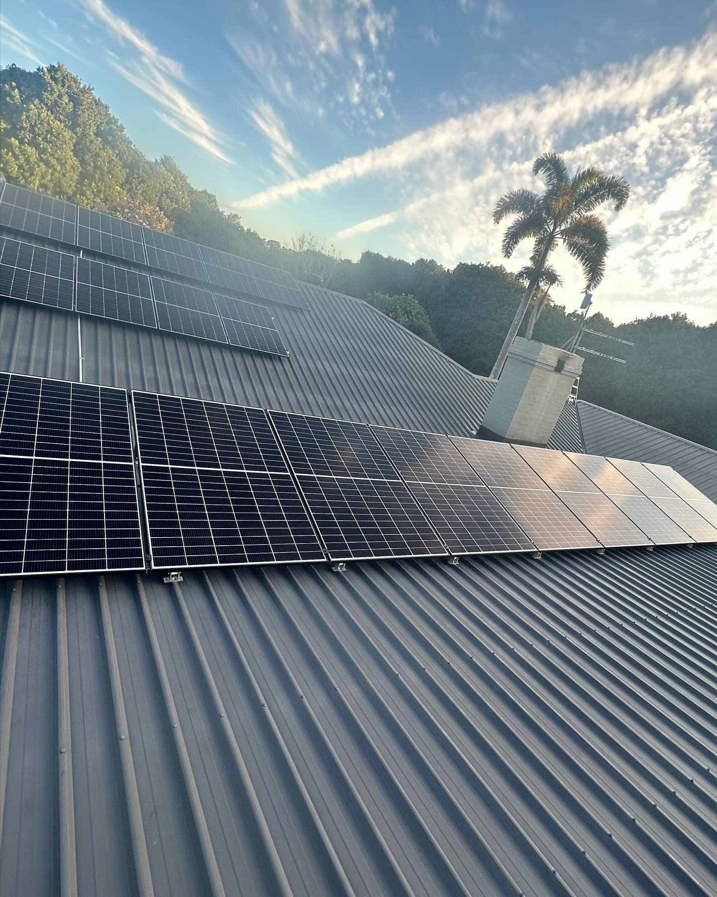 Solar Panels on a Corrugated Metal Roof at Sunrise With Trees and Sky in the Background — Grand Casa Electrical Solar & Batteries In Armidale, NSW