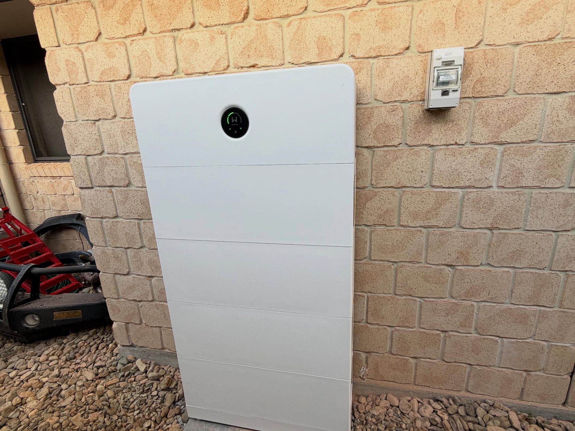 Tall White Outdoor Utility Cabinet Mounted on a Stone Wall With a Small Round Vent Near the Top — Grand Casa Electrical Solar & Batteries In Armidale, NSW