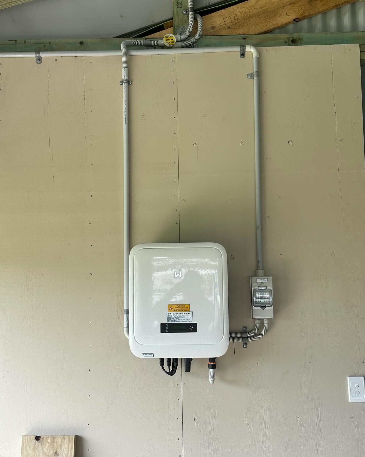 A Solar Battery Terminal Is Hanging On A Wall Next To A Pipe — Grand Casa Electrical Solar & Batteries In Lismore, NSW