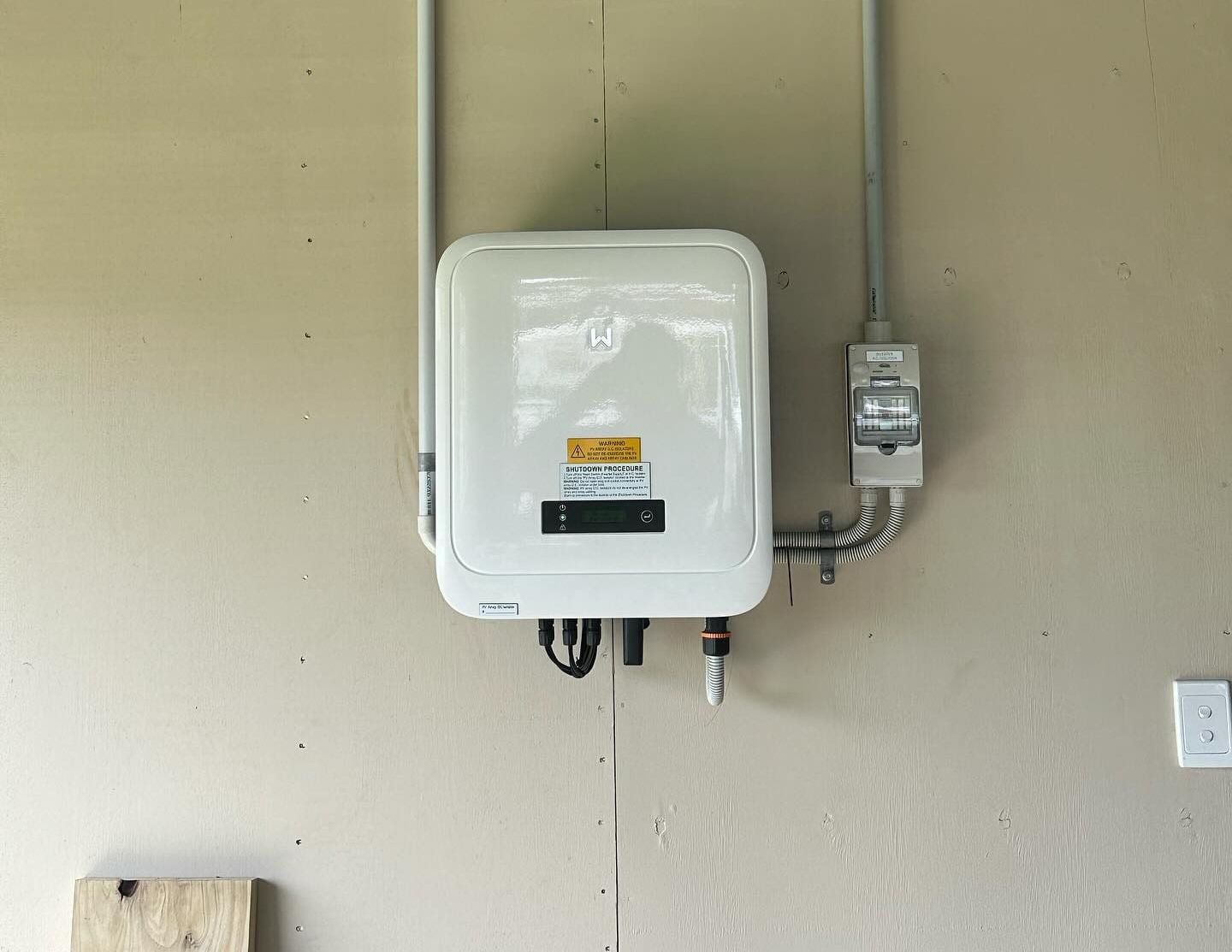 A Solar Battery Terminal Is Hanging On A Wall Next To A Pipe — Grand Casa Electrical Solar & Batteries In Byron Bay, NSW