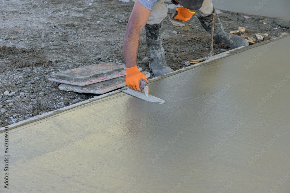 Worker in reflective vest using a hose to clean a street curb outside a house.