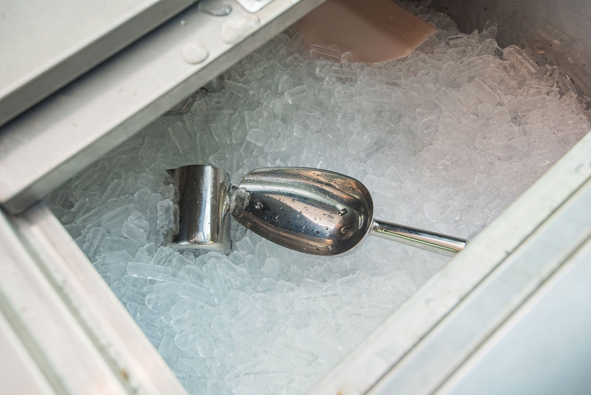 Ice bucket filled with ice and a metal scoop.