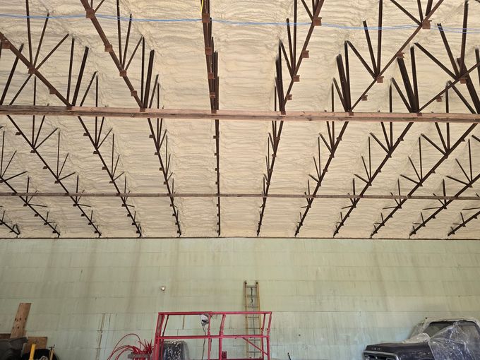 Interior of unfinished building with exposed ceiling beams and a red scaffolding lift below