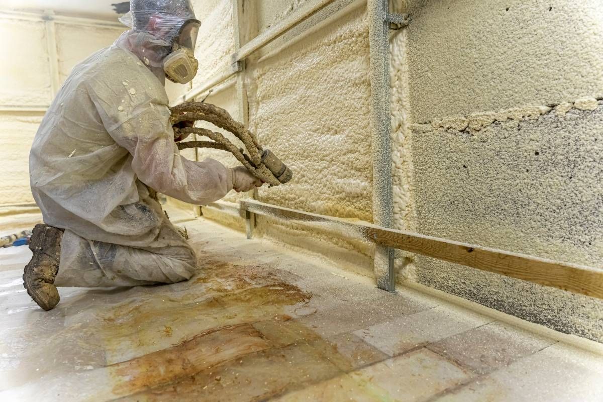 Suited worker insulates the walls with polyurethane spray foam