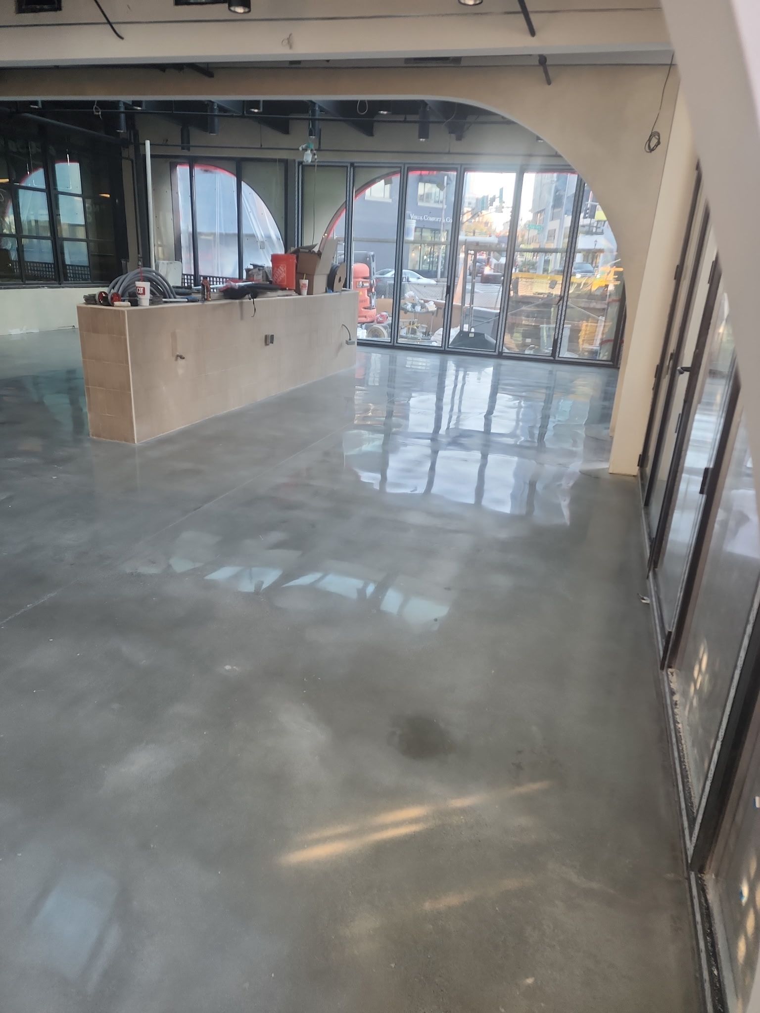Empty indoor storefront with glossy gray floor and large front windows letting in daylight.