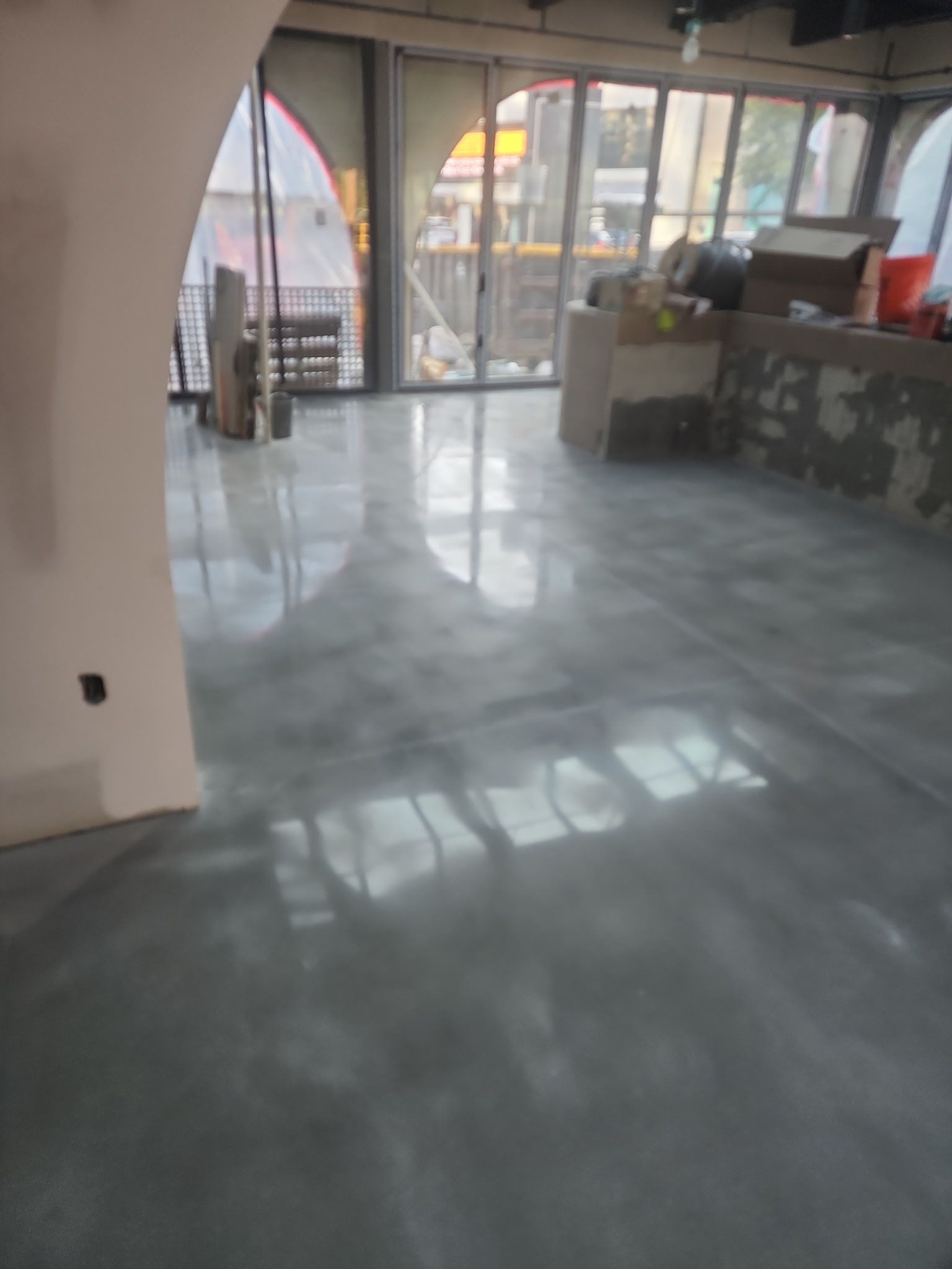 Empty storefront interior with glossy gray floor and large front windows overlooking the street