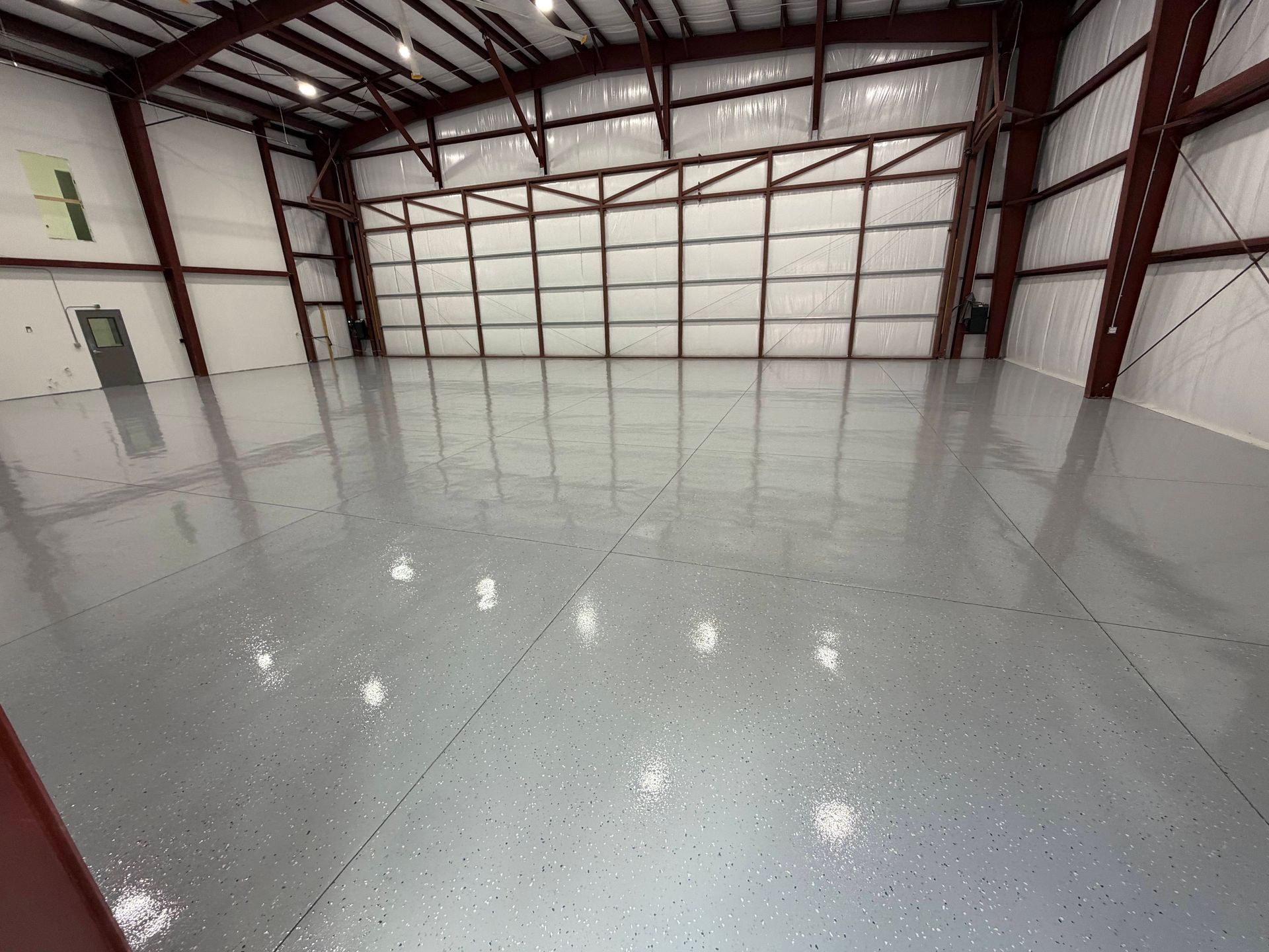 Empty industrial warehouse with white epoxy floor and metal wall framing
