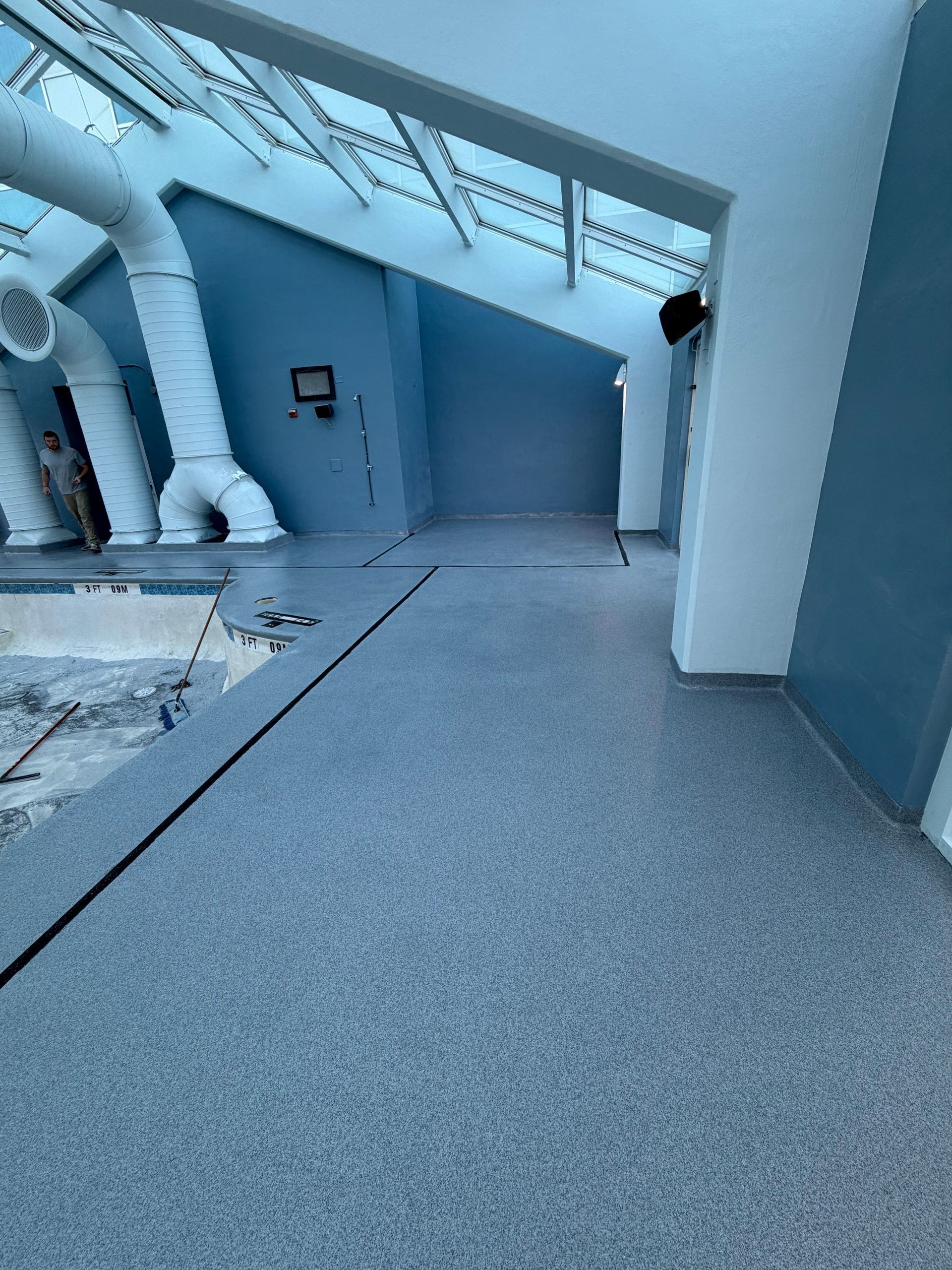 Modern industrial interior with blue walls, gray carpet, exposed ducts, and a doorway under a sloped ceiling