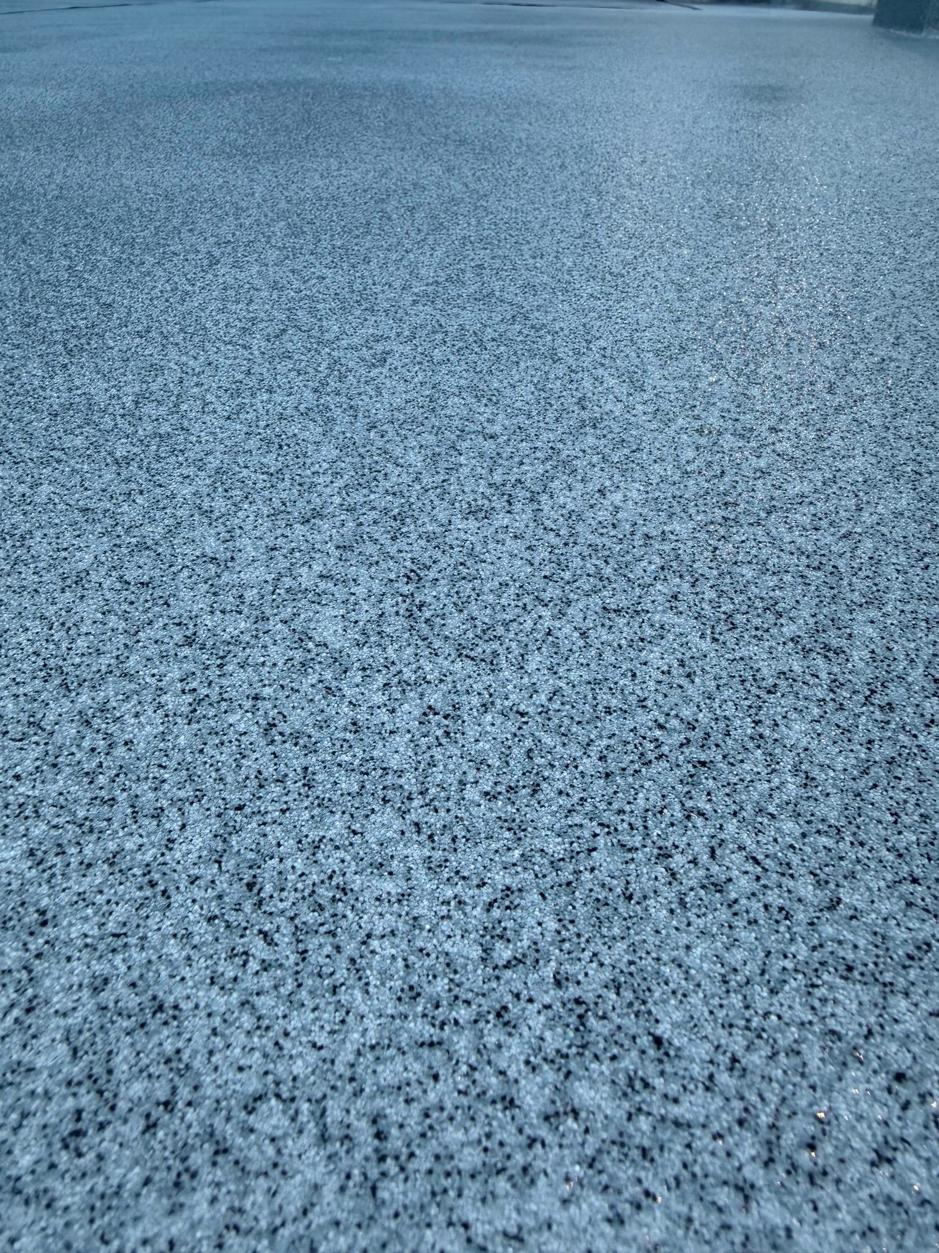 Blue-gray textured surface covered in tiny white specks, like frosted pavement or gravel
