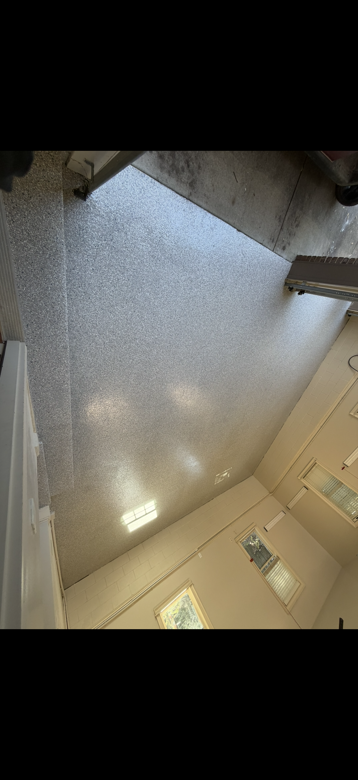 Ceiling view with bright skylight, speckled surface, and hanging string lights in a room