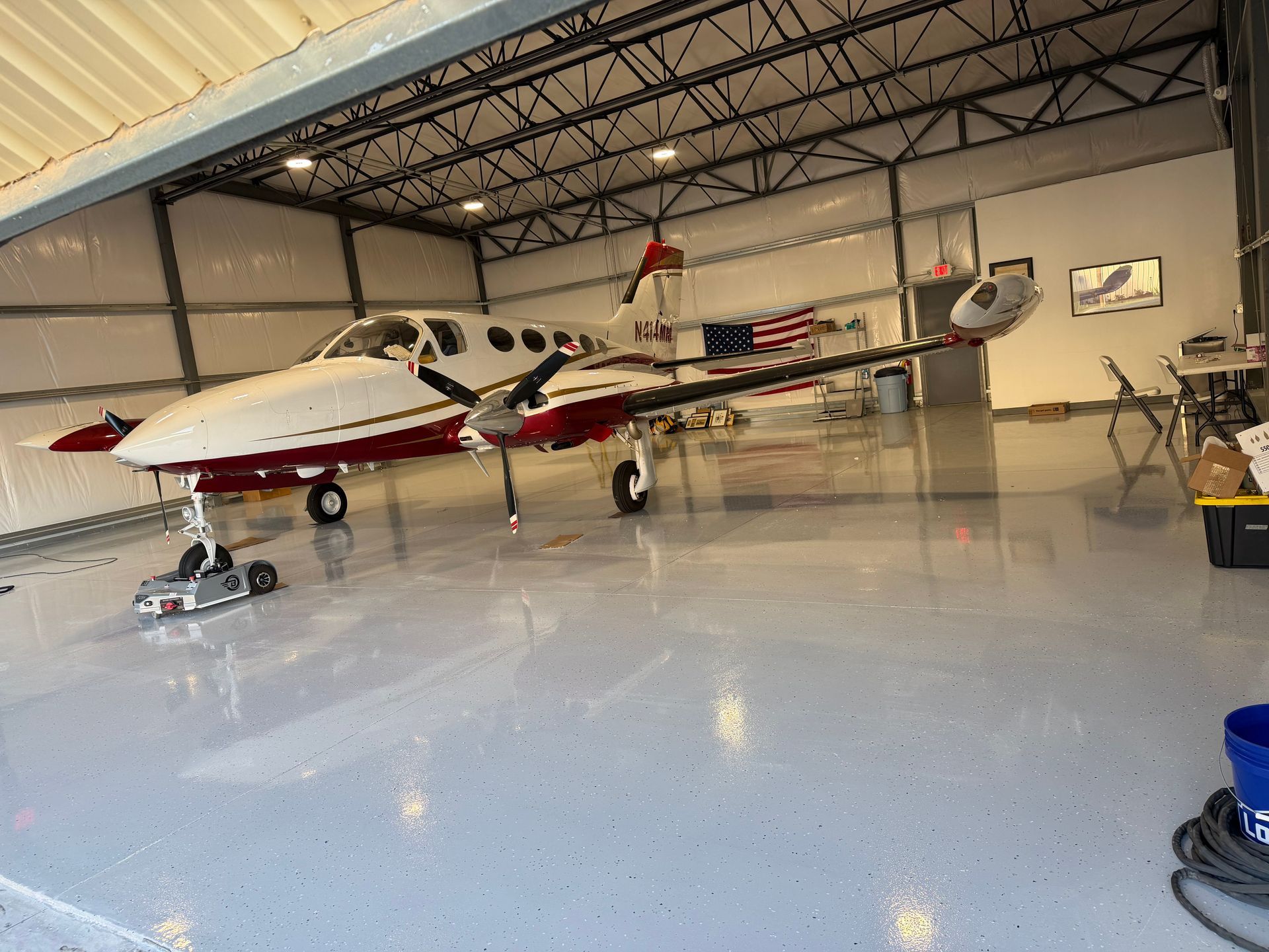 Small red-and-white twin-engine airplane parked inside a hangar on a polished floor