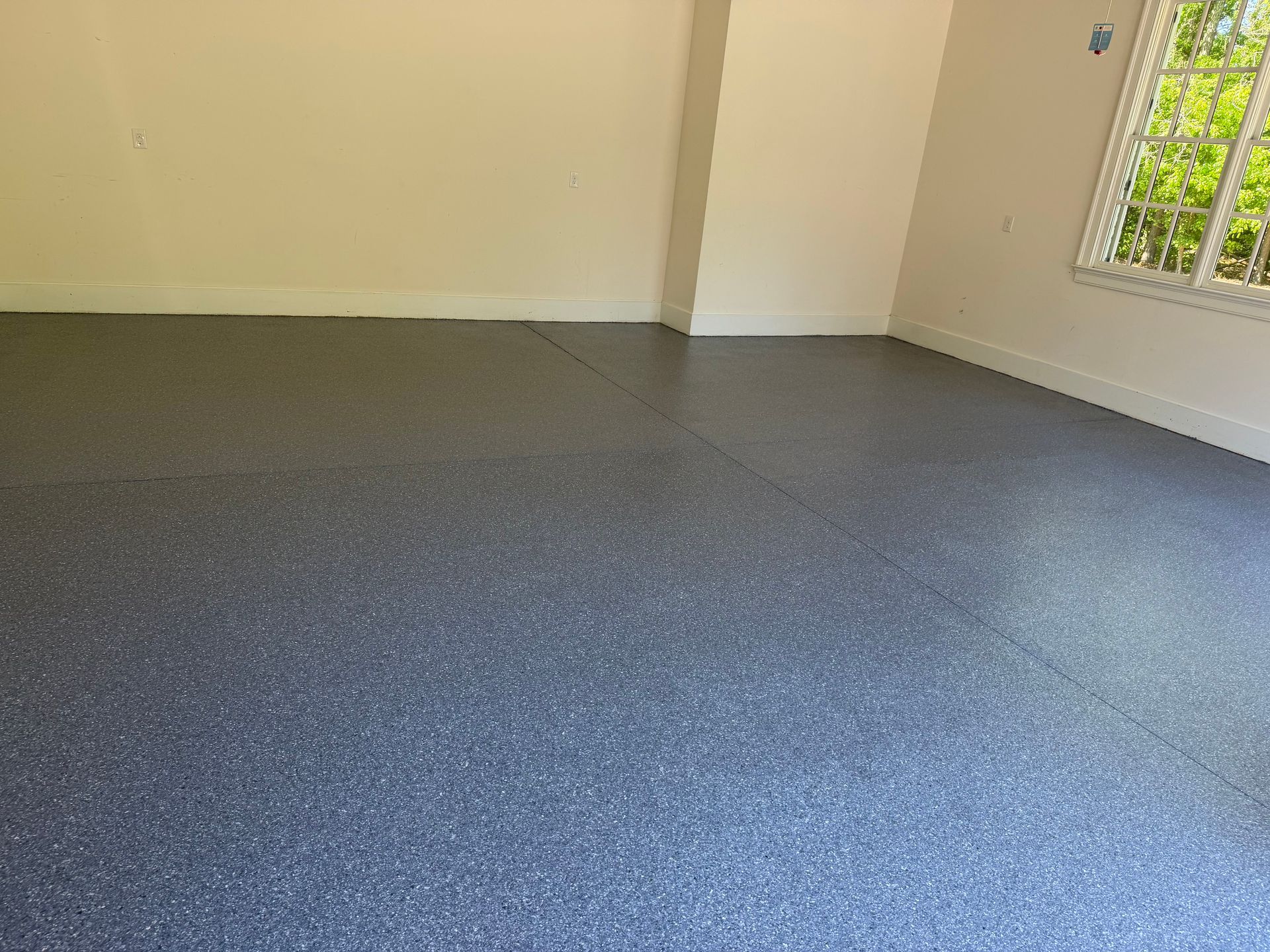 Empty room with blue-gray carpet, beige walls, and a window on the right.