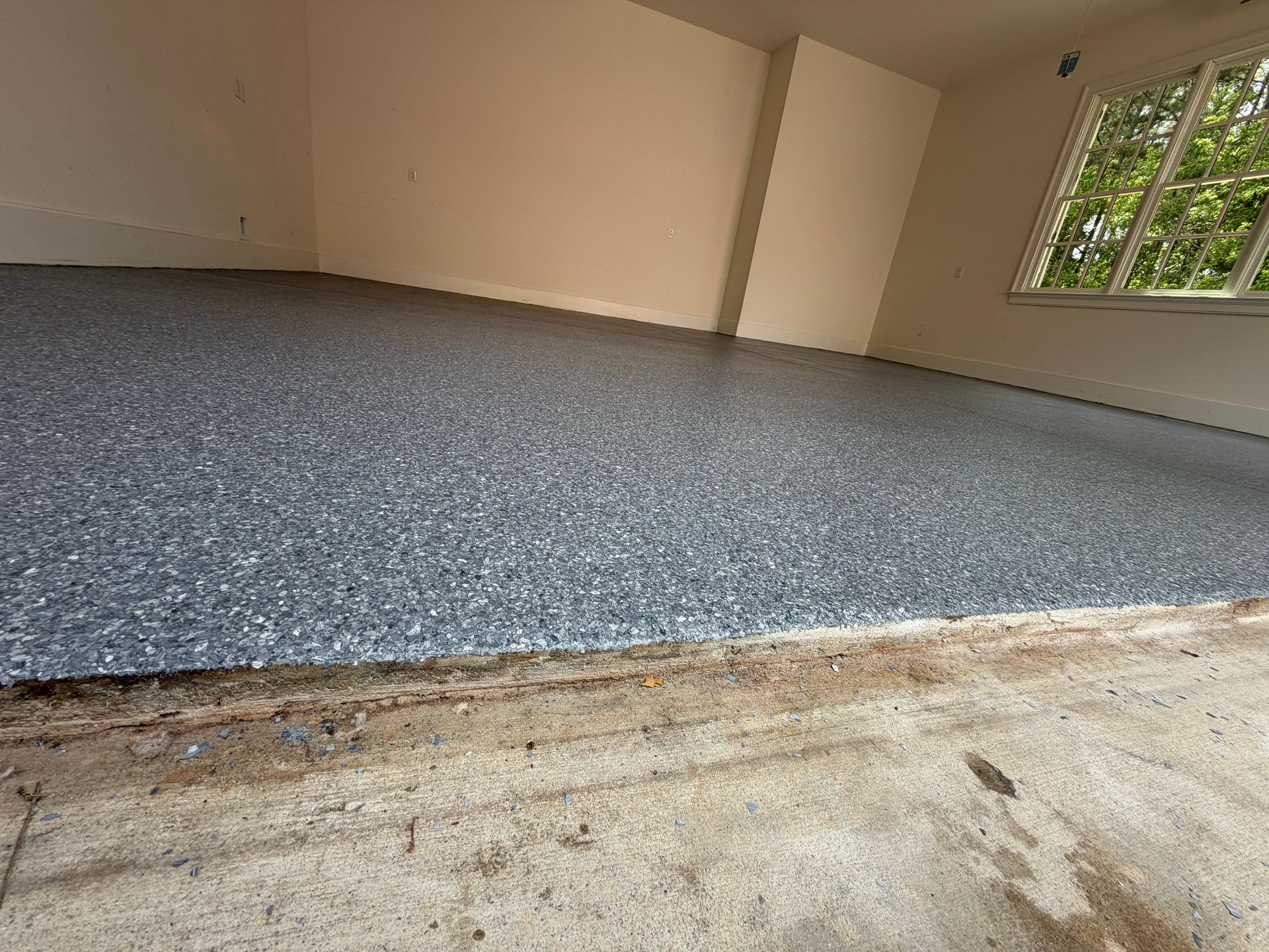 Empty room with blue-speckled carpet and beige walls, viewed from a doorway.