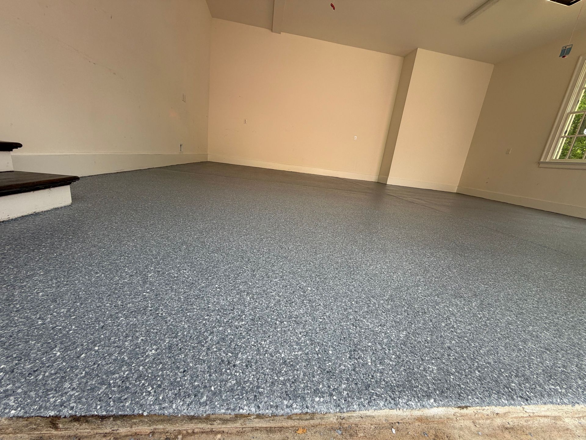 Empty room with gray carpet, beige walls, and a window on the right.