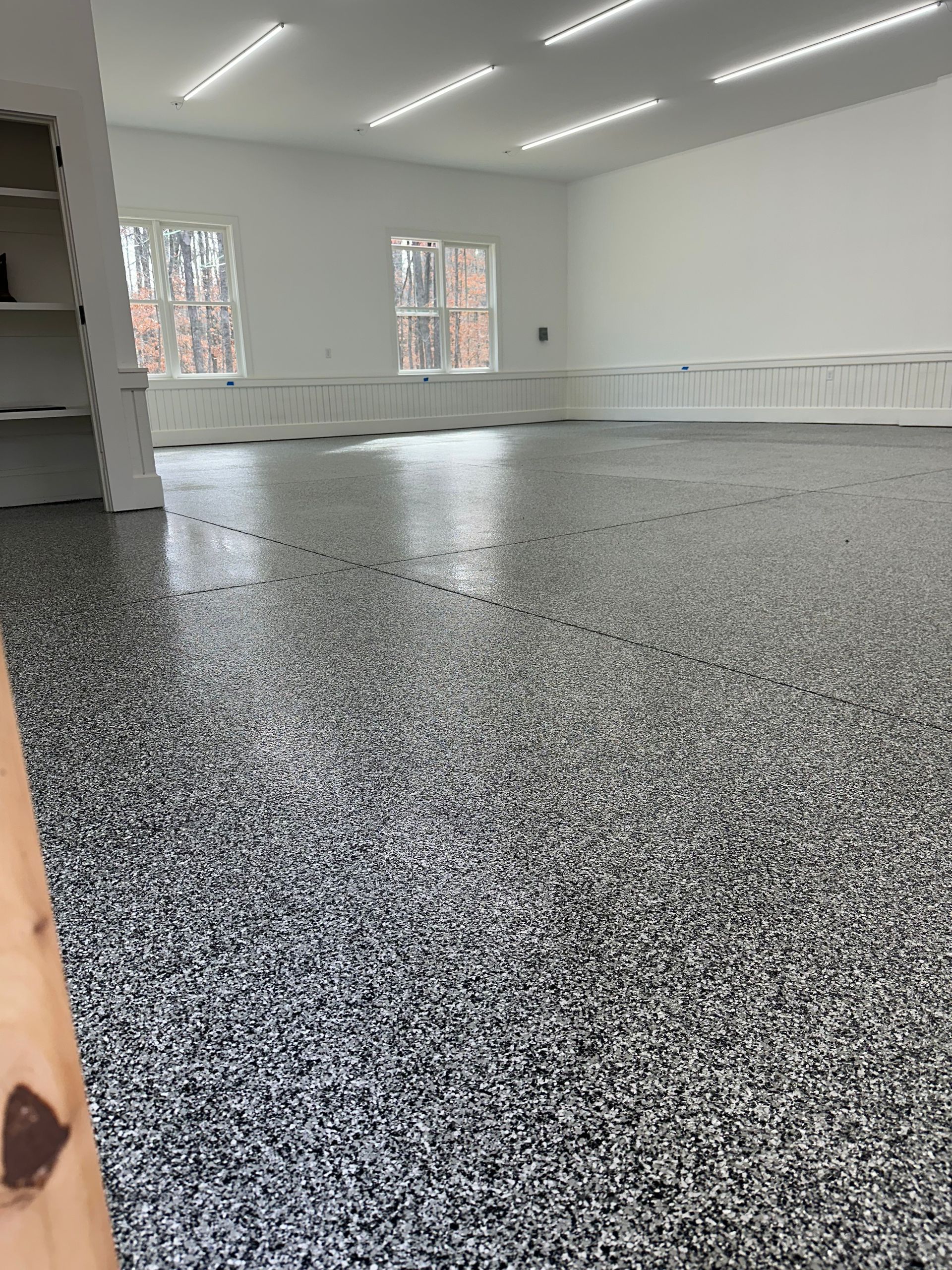 Empty bright room with speckled gray floor, white walls, and large windows.