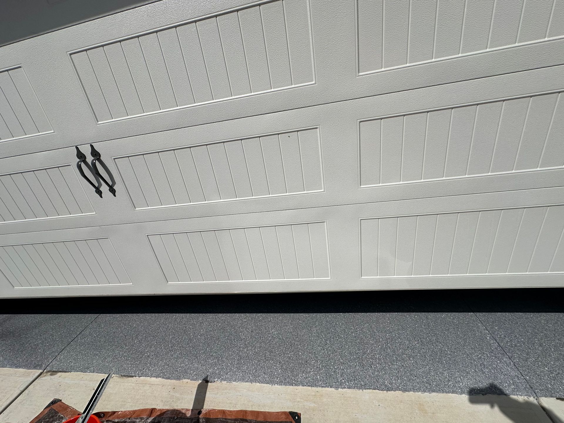 White garage door with black handle and red curb in front