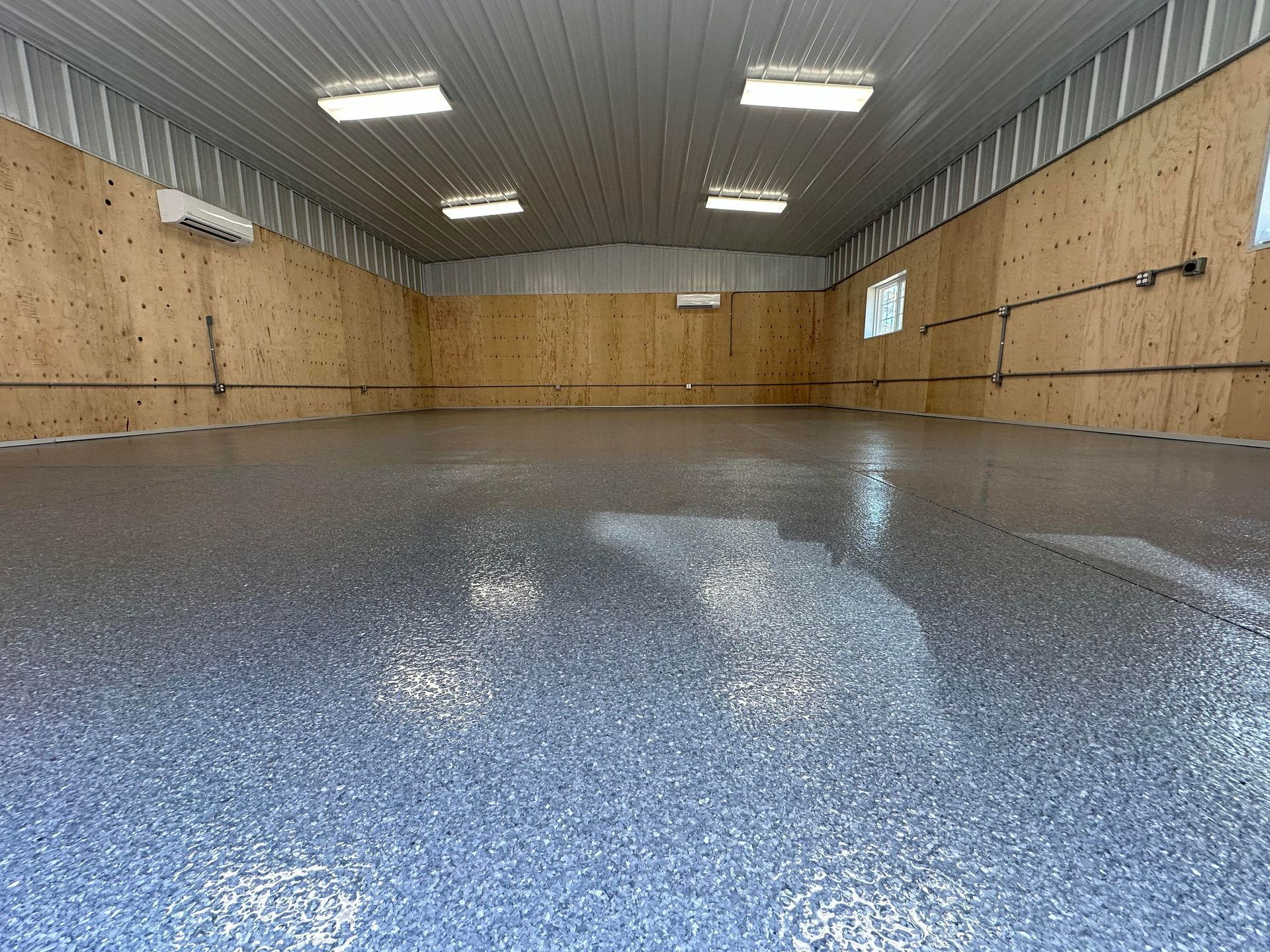 Shiny gray warehouse floor with scattered debris and reflections in a large empty indoor space