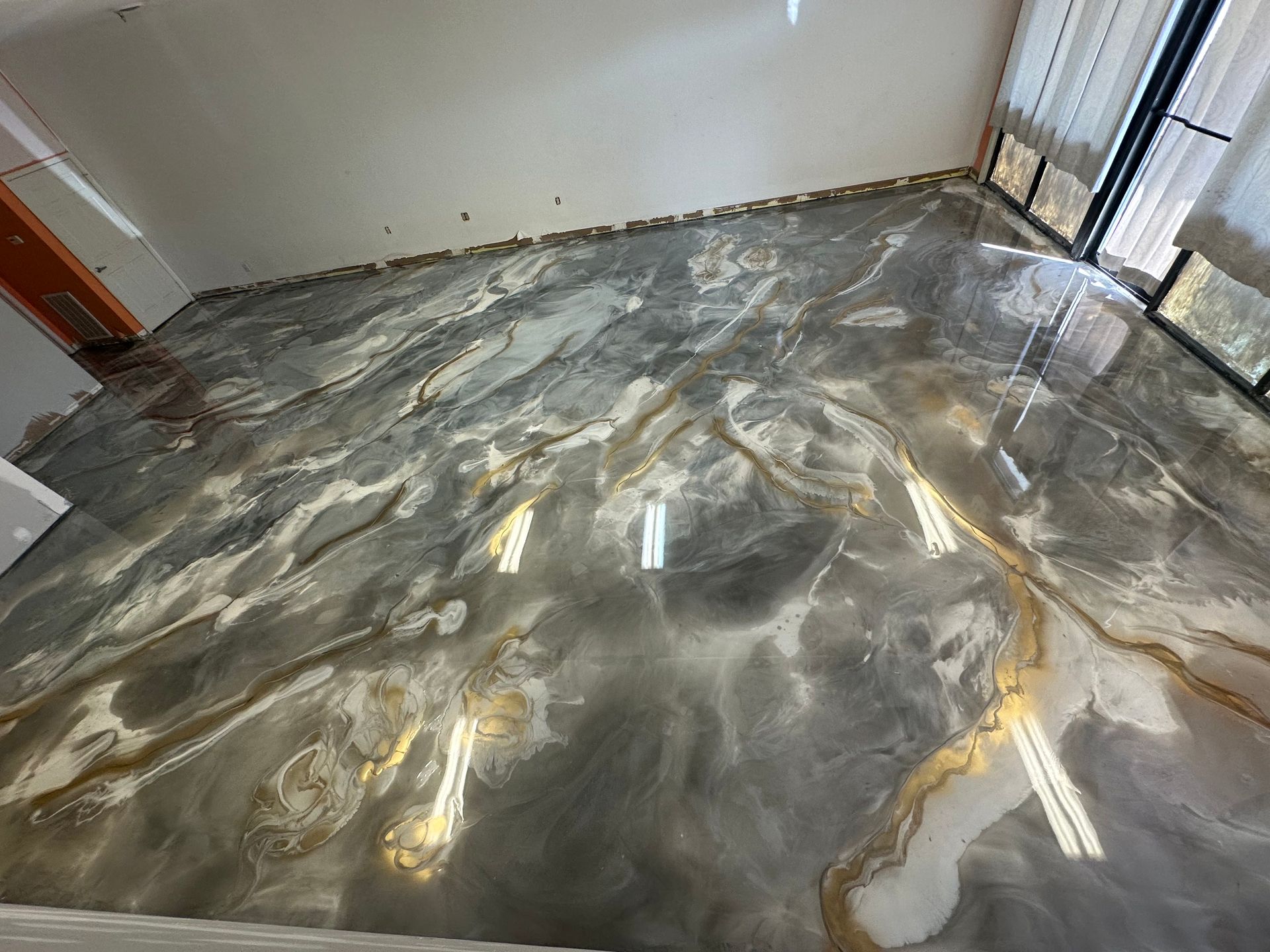 Empty room with a polished gray and gold epoxy floor and white walls