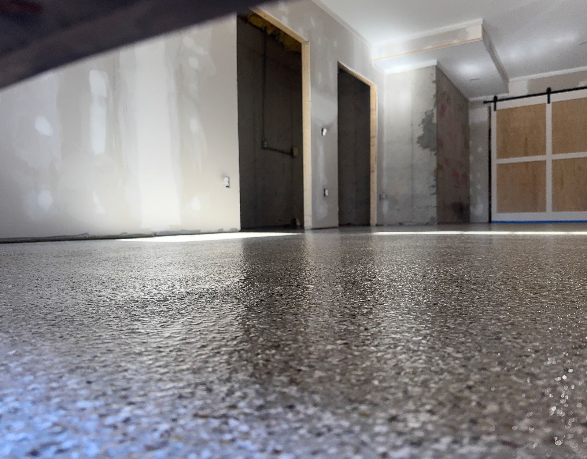 Low-angle view of a bare hallway with closed doors and a partially covered window