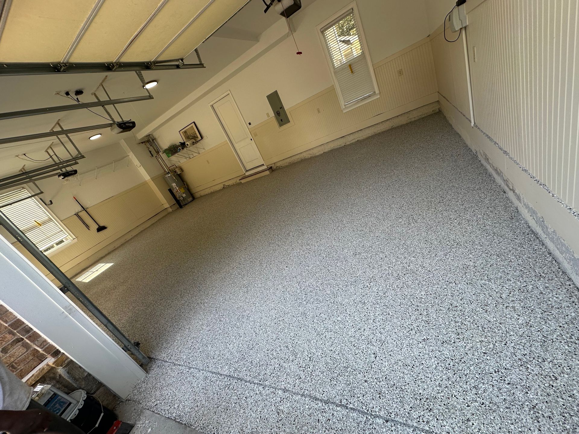 Empty beige garage with speckled epoxy floor and overhead door tracks