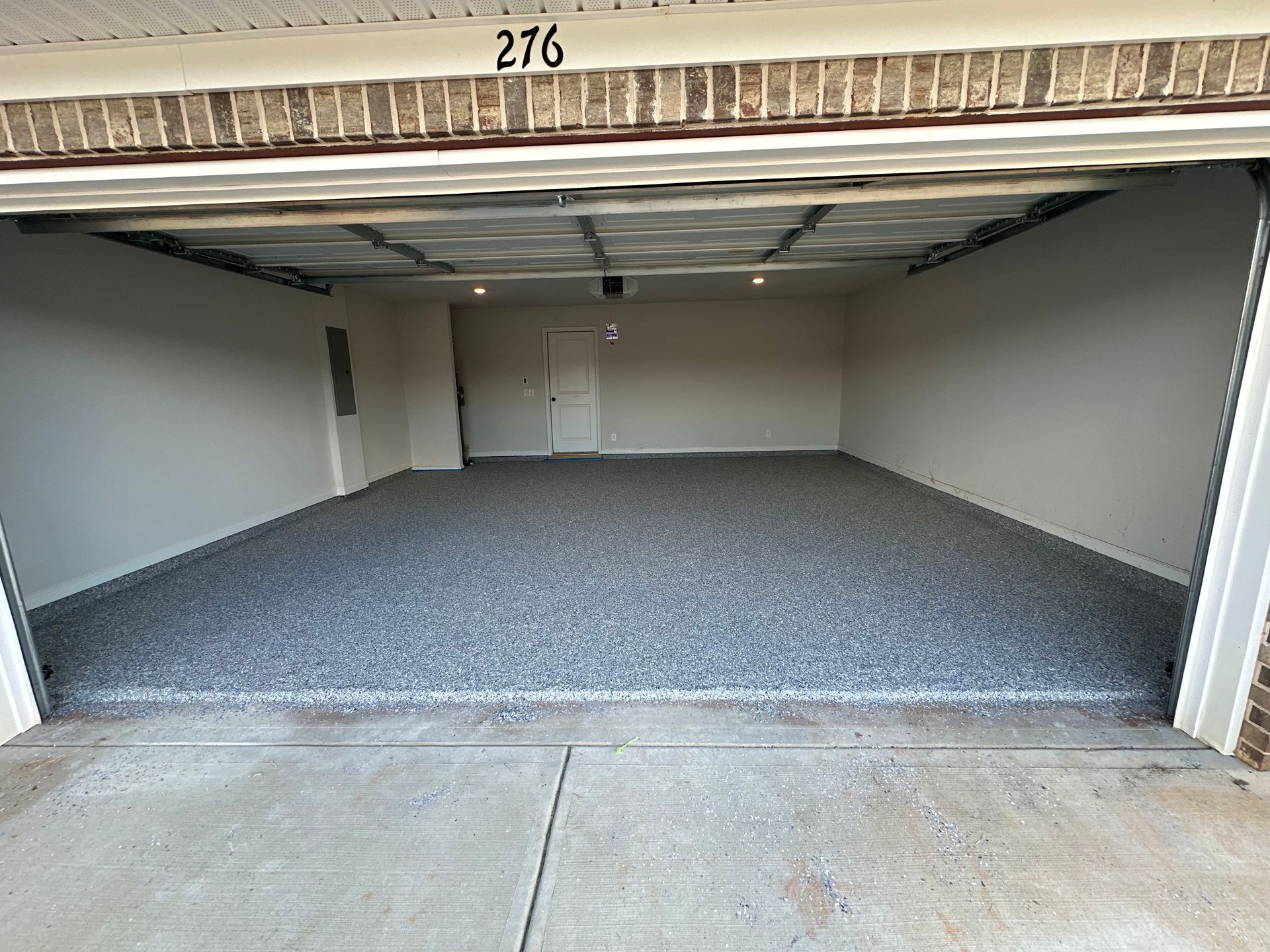 Open empty garage unit with gray carpet and concrete floor, numbered 276.