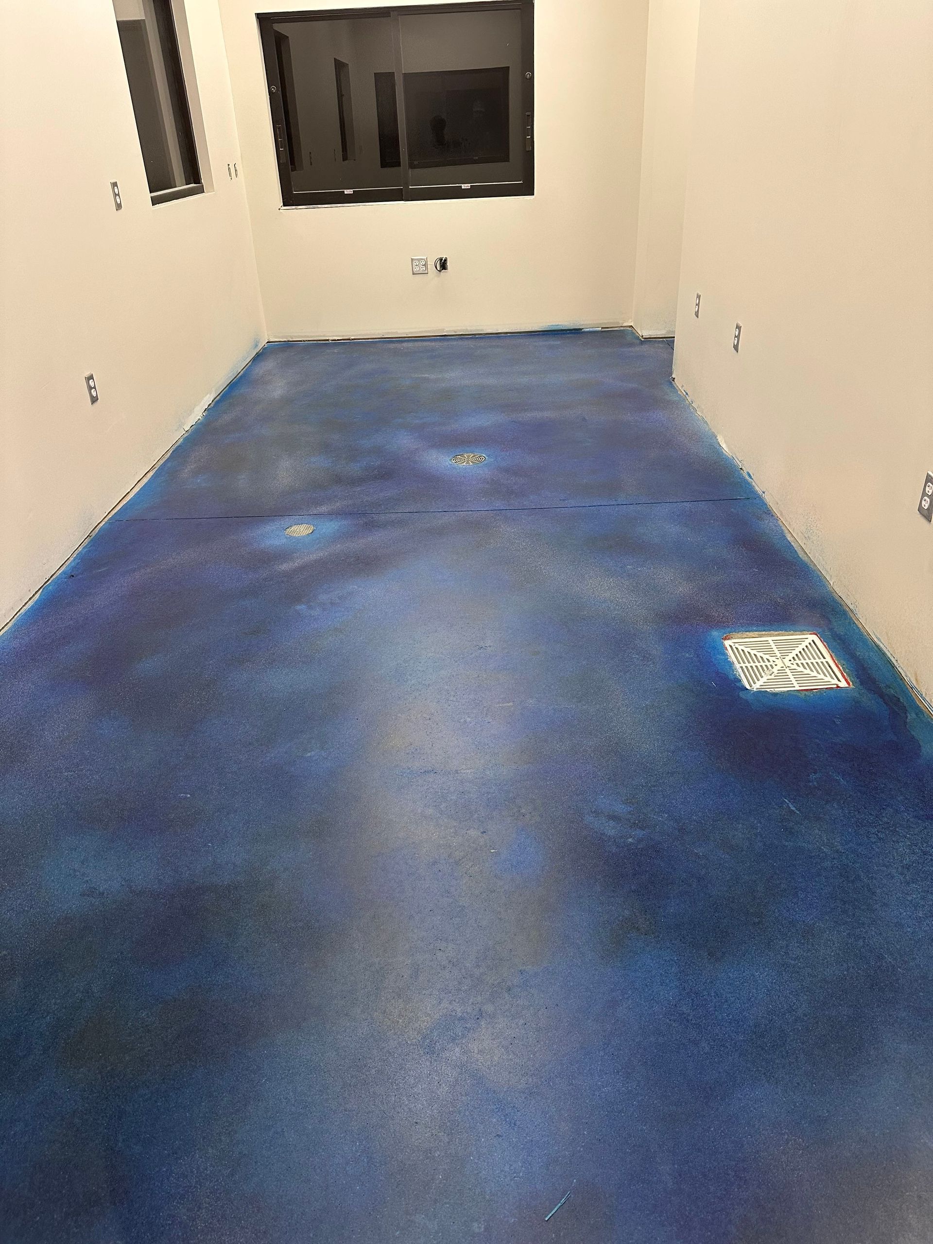 Empty room with blue carpet, white walls, and a window at the far end.