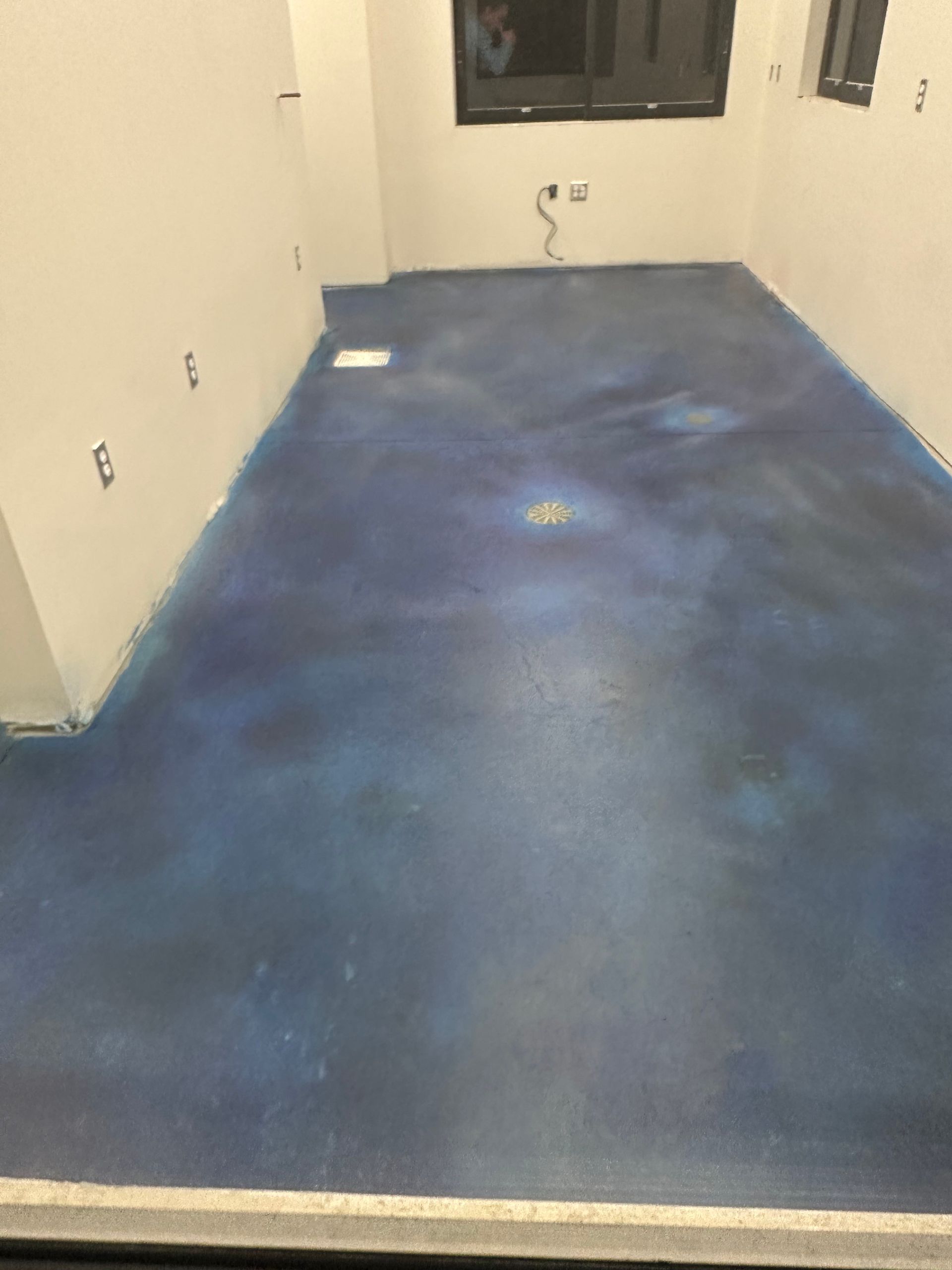 Empty room with blue carpet, beige walls, and a window at the far end.