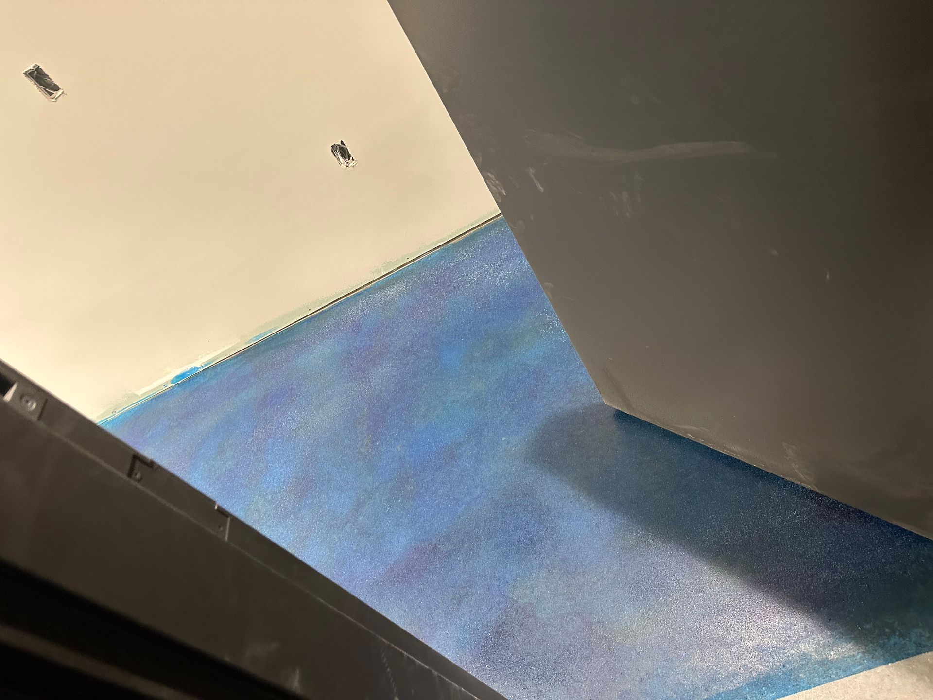 Blue floor beside beige wall and dark cabinet in a room corner