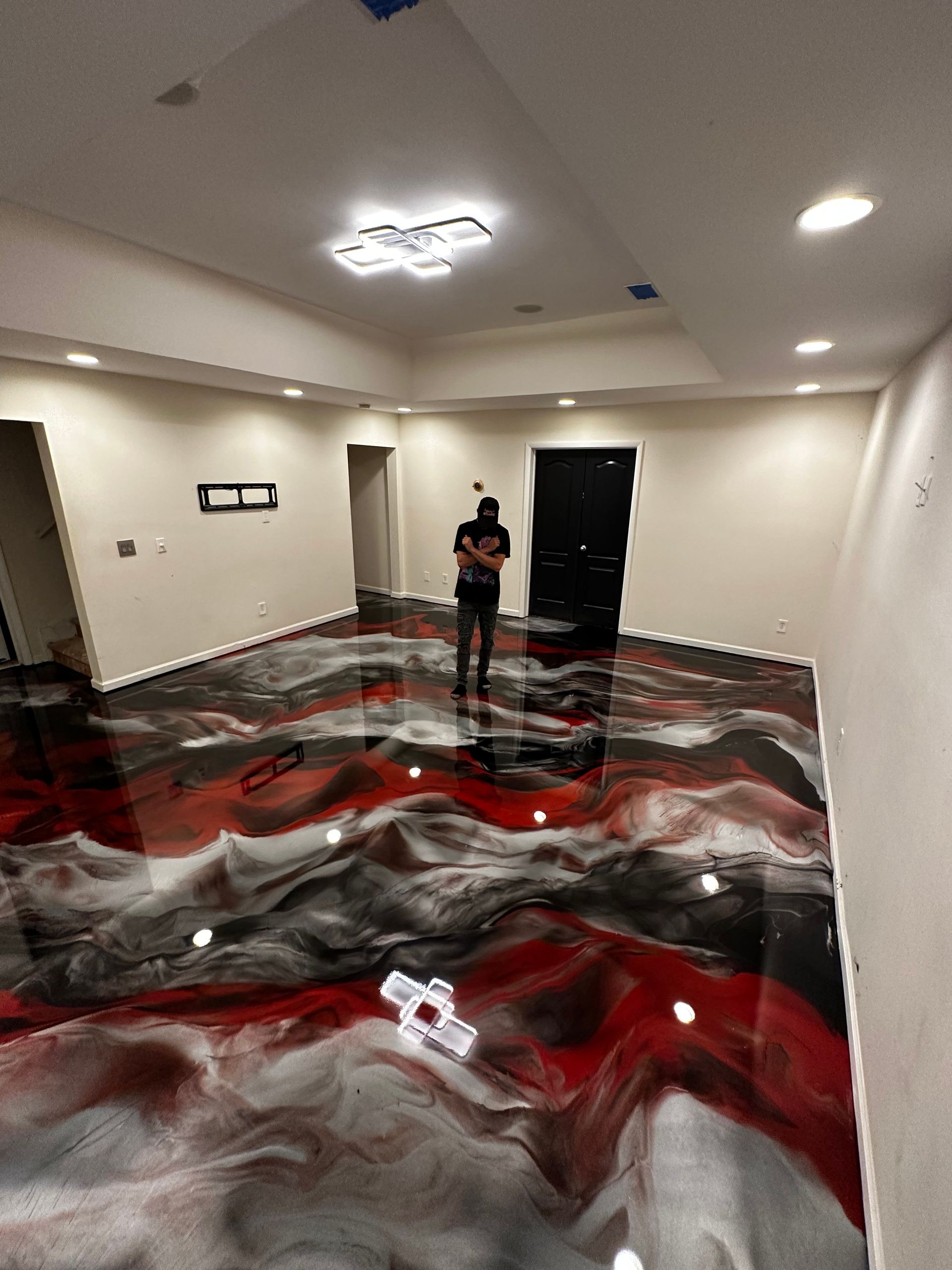Office hallway with black, white, and red wavy floor design and a person standing near the back wall