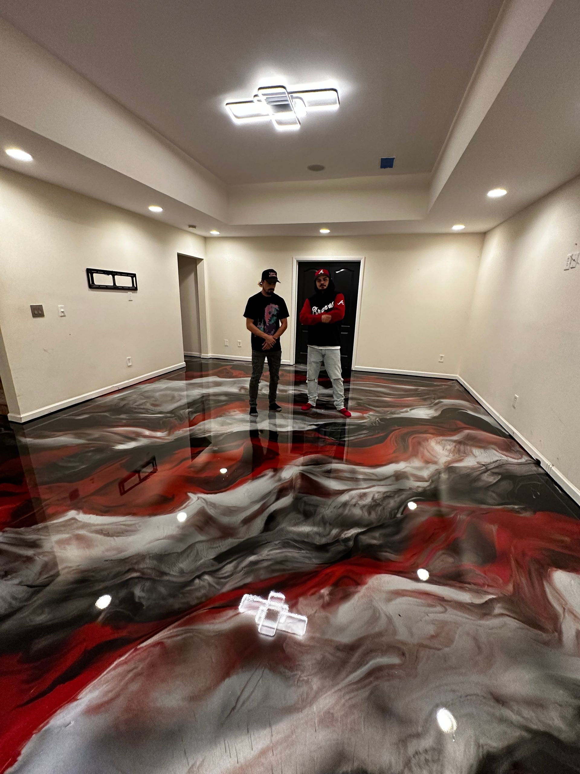 Two people standing in a room with a glossy red, black, and white marbled floor design